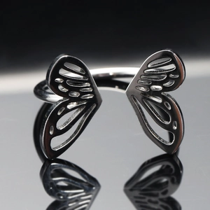 Détail macro montrant les ailes de papillon ajourées sur une bague en acier inoxydable