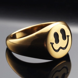 Polished gold signet ring with black melting smiley face pattern on black reflective surface