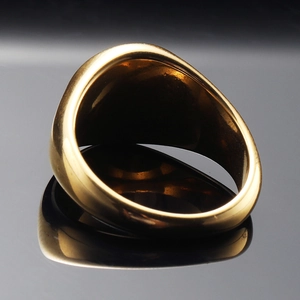 Macro close-up of wide gold stainless steel signet ring with polished mirror finish
