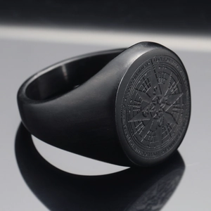 Macro shot of matte black stainless steel ring featuring a compass star engraving and text