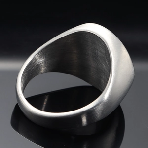 Macro shot of brushed stainless steel signet ring with elegant reflection on black surface