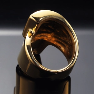 Vista macro di un anello largo dorato con finitura lucida a specchio su base nera