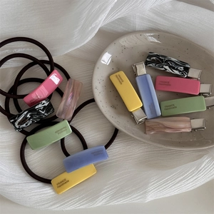 Macro shot of candy-colored acetate hair clips and elastics on a ceramic plate