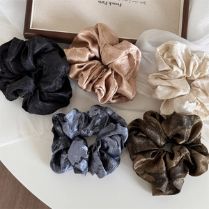Detailed macro view of 5-piece retro silk texture scrunchies with ink wash tie-dye patterns