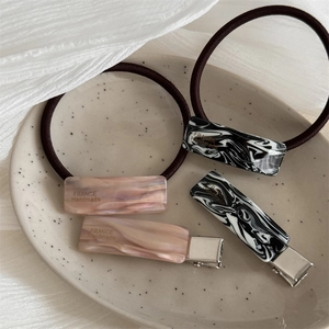 Detail of marble pattern resin hair clips and elastic hair ties with France Handmade logo