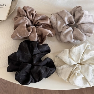 Detail view of 4-pack ink-pattern satin scrunchies in brown, grey, black and white
