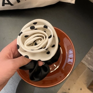 Detailed close-up of a handmade black and white polka dot camellia flower hair scrunchie