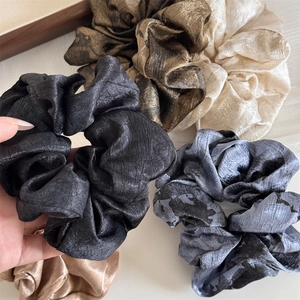 Detailed view of crinkled ink-wash texture and silky sheen on multi-color scrunchies