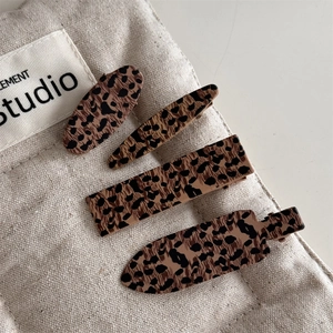 Set of four vintage leopard print hair clips in various shapes on a canvas background