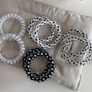 Detailed macro view of polka dot spiral hair ties in black, white, and clear resin colors