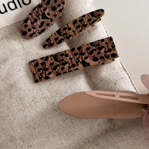 Detailed macro view of leopard print hair clips and beige matte finish accessories