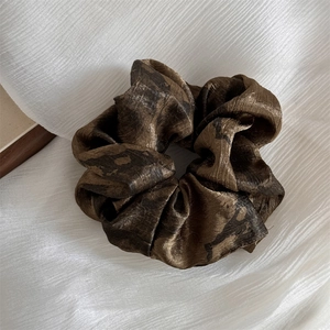 Detail view of large silk-textured scrunchie with dark brown and black ink-wash dye pattern