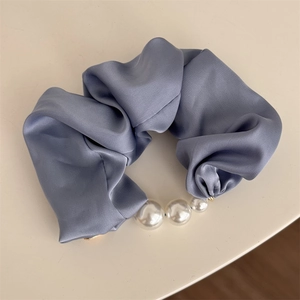 Détail d'un chouchou en satin bleu avec perles dégradées et texture en soie élégante