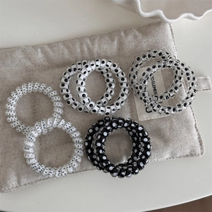 Detail of spiral hair ties featuring black and white polka dots and marble patterns