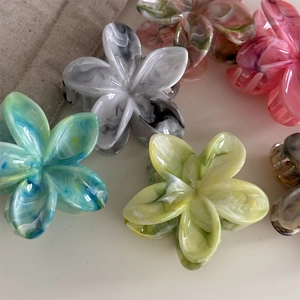 Bunte Blumen-Haarklammern mit Marmortextur auf weißem Hintergrund präsentiert