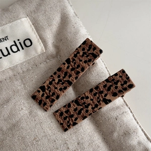 Close-up of rectangular leopard print duckbill hair clips on beige linen background