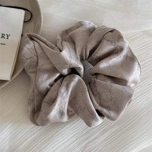 Detail of satin scrunchie featuring elegant grey ink marble texture and soft silk luster