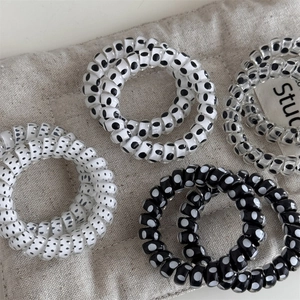 Black and white polka dot spiral hair ties set on a textured fabric surface