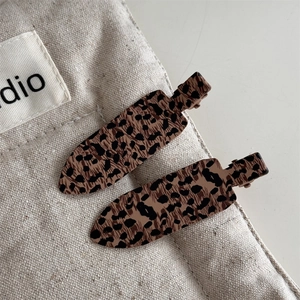 Detailed macro view of two leopard print hair clips on a textured canvas background