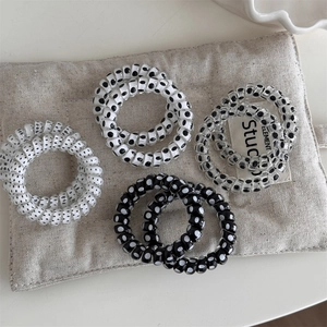 Polka dot spiral hair ties set with black and white patterns on textured fabric