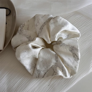 Detailed view of the ink marble texture on a satin fabric oversized scrunchie