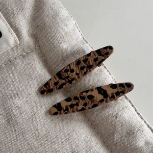 Close-up of stylish leopard print hair clips on a cream canvas background for women