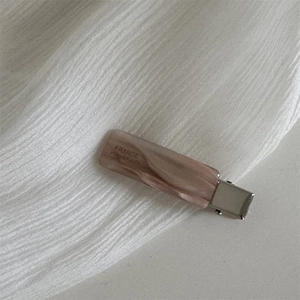 Close-up of handmade pink marble acetate duckbill hair clip with silver metal base