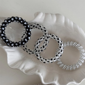 Detailed view of four elastic polka dot spiral hair ties in a shell-shaped ceramic tray