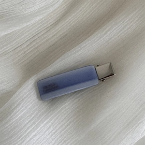 Close-up of lilac acetate hair clip with France Handmade engraving on wavy fabric