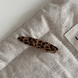 Detailed view of leopard print hair clip on beige linen texture background