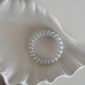 Detailed view of polka dot spiral hair tie on a white shell decorative tray
