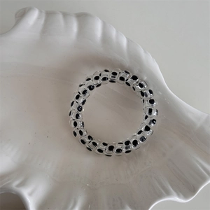 Detailed view of elastic spiral phone cord hair tie with black polka dot design on tray