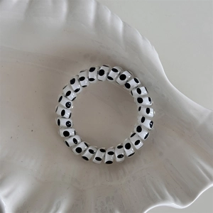 Detailed shot of white spiral hair tie with black polka dots on a shell decorative tray