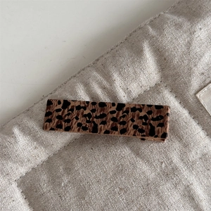 Macro shot of a rectangular leopard print hair clip on a quilted fabric background