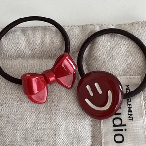 Detailed close-up of red resin bow and smiley face charm on elastic hair bands