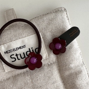 Detail von handgemachter roter Harz-Blumen-Haarspange und elastischem Haargummi Set auf Leinen