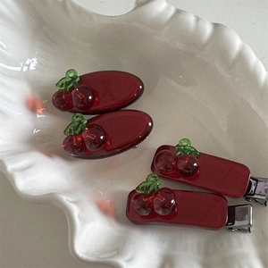 Detail of red cherry hair clips with glitter resin in a white shell-shaped dish