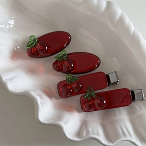 Detail view of four cherry hair clips in a shell tray with red translucent finish