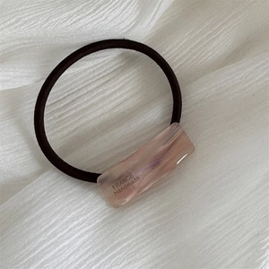 Detail of pink marble resin hair tie with thick black elastic and gold handmade text
