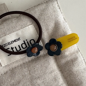 Detailaufnahme des dunkelblauen Acetat-Blumenhaargummis und der Haarspange auf Segeltuch