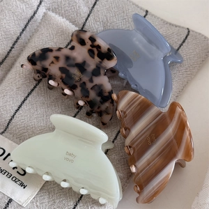 Detailed macro view of four acetate claw clips in marble and jelly textures on fabric