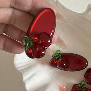 Detailed macro view of translucent red cherry hair clip with 3D fruit motif and glossy finish