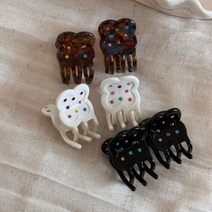 Detail view of acetate flower hair clips with colorful rhinestones on linen fabric