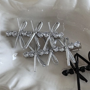 Detailed macro view of crystal heart-shaped stones and bow ribbon on a metal hair clip
