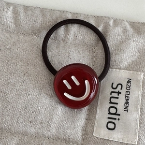 Close-up of elegant burgundy acetate hair ring featuring a minimalist white smiley face icon