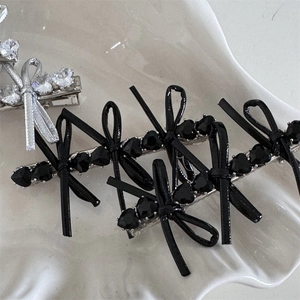 Close-up of heart crystal and leather bow hair clips on a white ceramic plate