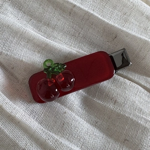 Detailed view of the red translucent cherry hair clip on white textured fabric