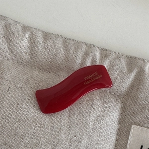 Detailed close-up of wavy dark red acetate hair clip with FRANCE Handmade lettering