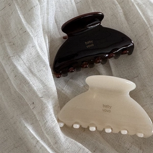 Detailed view of jelly texture tortoise and cream acetate hair claws on linen fabric