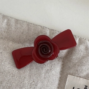 Detailed macro view of an elegant burgundy resin rose hair clip on a canvas texture